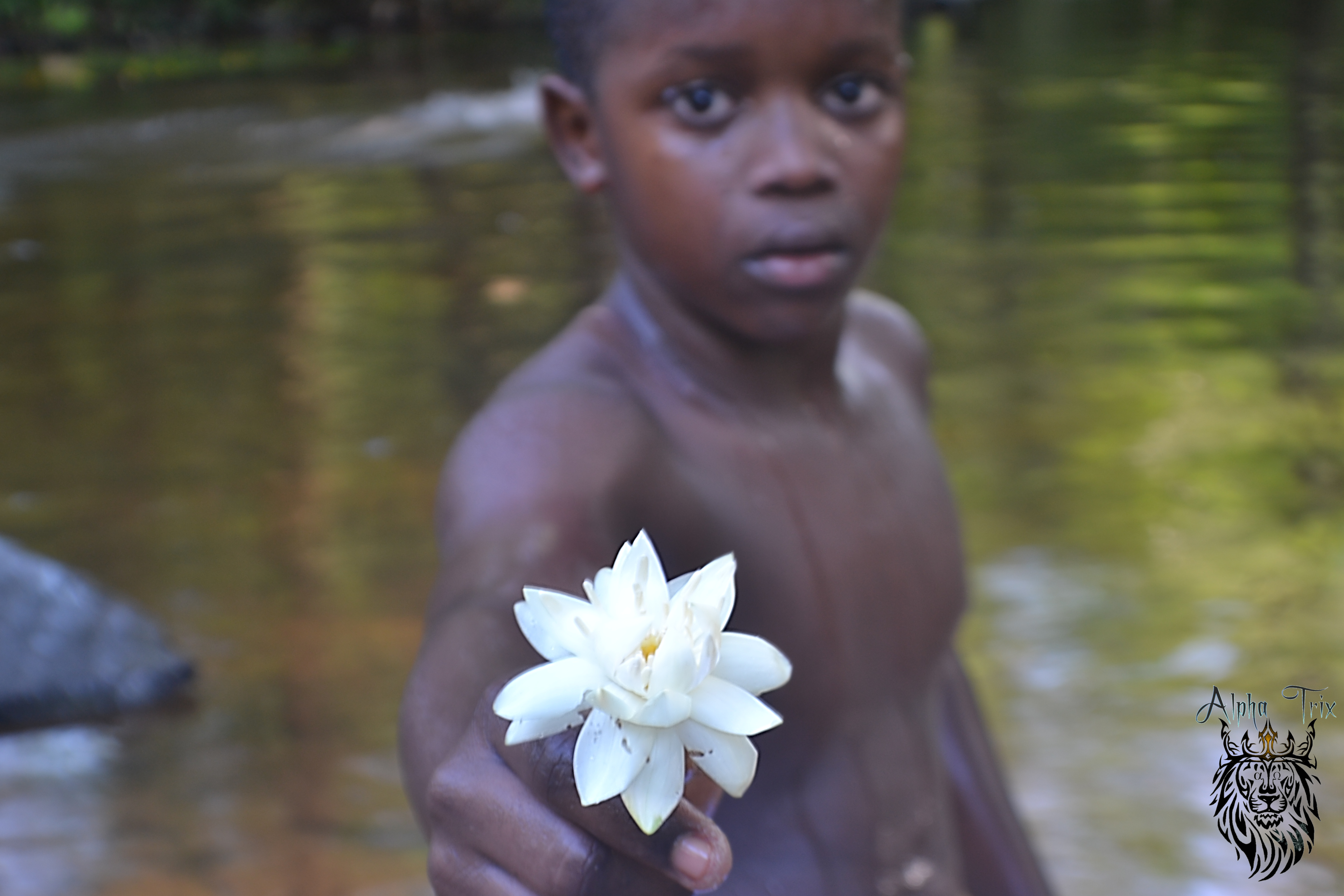 Fotografia de uma das crianças integrante do grupo de matriz africana, sendo ela uma das crianças que tocam nos festejos tradicionais, esta fotografia foi em local de banho da comunidade sendo este um pequeno riacho de águas límpidas que proporciona profundidade segura para crianças acompanhadas de adultos.