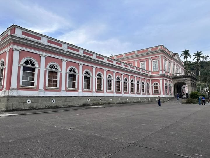 Museu Imperial de Petrópolis
Gustavo de Castro Praxedes
Subir a serra e visitar a cidade de Petrópolis no Estado do Rio de Janeiro, já é um passeio e tanto. Sem sombra de dúvidas, observar as montanhas, a paisagem, os pequenos córregos, o céu azul ou nublado, é encantador. Petrópolis por si só, já é mágica, nos faz voltar ao passado, nos encanta com seu charme de cidade imperial. As Casas do centro histórico, construída por imigrantes europeus que colonizaram a cidade, refletem o estilo arquitetônico eclético, com influência do neoclássico.
Visitar o Museu de Petrópolis, é conhecer como vivia a família Imperial brasileira, é passear por grandes salões e ver antigos moveis, quadros, porcelanas e adereços, ou melhor, é simplesmente fazer uma viagem no tempo pelo antigo Palácio de Verão do imperador brasileiro Dom Pedro II.
Na entrada, temos que colocar grandes pantufas nos pés, tudo isso para não danificar o assoalho. Logo, inicia-se a grande viagem no tempo. Salas e mais salas, com objetos que vemos apenas nos livros de história.
O acervo do museu é constituído por peças ligadas à monarquia brasileira, objetos pessoais da família imperial. Na coleção, pinturas como o quadro a 